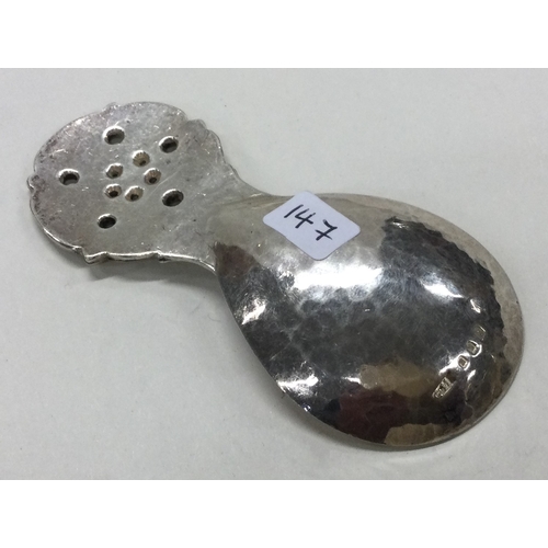 147 - GUILD OF HANDICRAFTS: A silver caddy spoon with floral and hammered decoration. Approx. 29 grams. Es... 