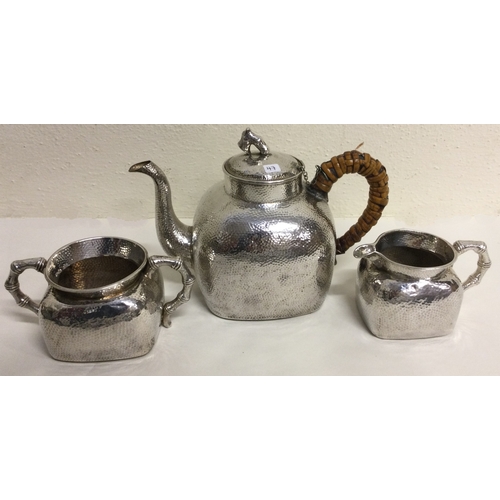 47 - A Chinese export silver three piece tea set of hammered design. Marked to base. Approx. 942 grams. E... 