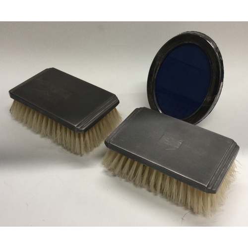 5 - A small pair of engine turned silver brushes together with a picture frame. Est. £30 - £40.