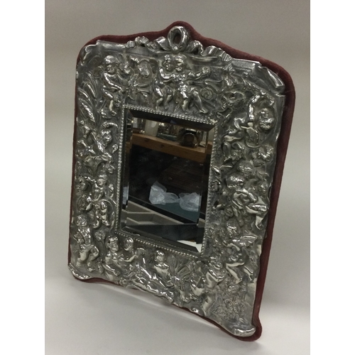 51 - A silver backed mirror embossed with cherubs. Est. £50 - £80.