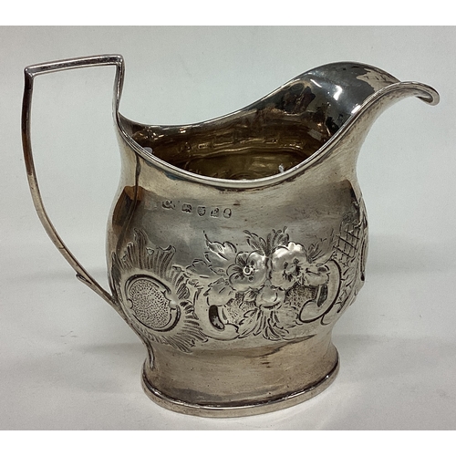 630 - A Georgian silver cream jug with chased decoration. London. Approx. 119 grams. Est. £50 - £80.