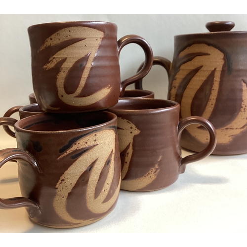 582 - A vintage stoneware tea set comprising a teapot and six cups in brown ground with wax resist patter.... 