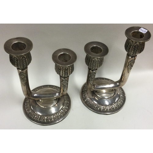 448 - A pair of silver candelabras with chased decoration. Approx. 1093 grams. Est. £150 - £200.