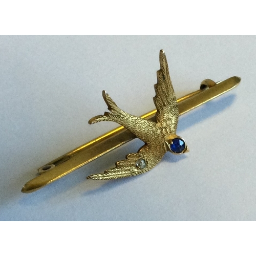 700 - A small 15 carat gold brooch in the form of a swallow with sapphire head. Approx. 4 grams. Est. £100... 