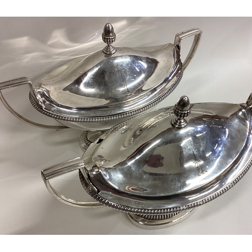 144 - A fine pair of Georgian silver tureens and covers with gadroon rims to reeded handles and crested ar... 