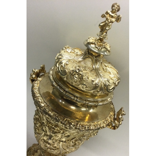 388 - A rare Edwardian silver gilt cup and cover heavily embossed with flowers to cherub finial. London 19... 