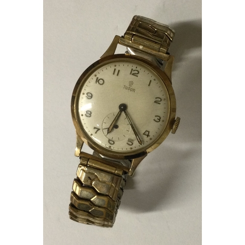 956 - TUDOR: A gent's 9 carat wristwatch with silvered dial on expanding strap. Est. £250 - £350.