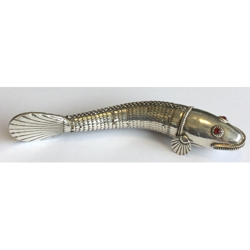 781 - A silver articulated figure of a fish with red eyes. Approx. 76 grams. Est. £120 - £150.