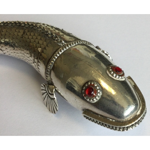 781 - A silver articulated figure of a fish with red eyes. Approx. 76 grams. Est. £120 - £150.