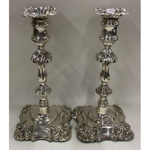 254 - A pair of William IV silver candlesticks with crested decoration. Sheffield 1834. By Thomas, James &... 