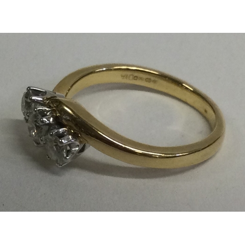 837 - A three stone cross over ring in 18 carat gold mount. Approx. 4 grams. Est. £100 - £150.