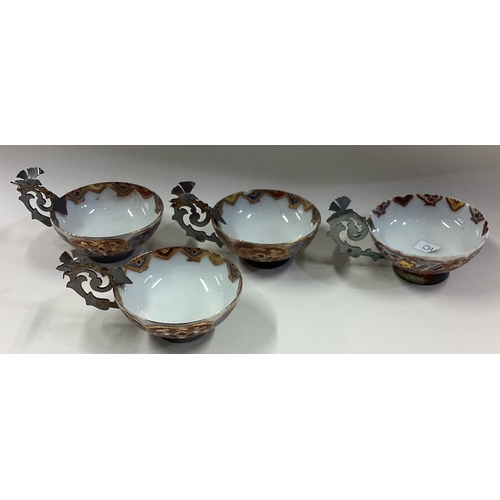 10 - A set of four silver mounted cups with pierced handles. Est. £60 - £80.