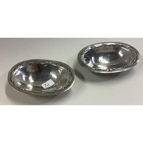 31 - GEORG JENSEN: A pair of chased silver dishes on feet. Approx. 34 grams. Est. £100 - £150.