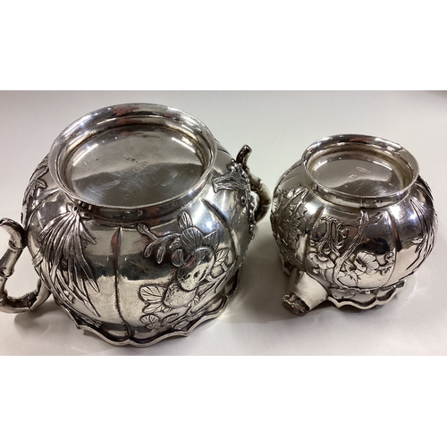 474 - A Chinese export silver sugar and cream set embossed with flowers. Character marks to base. By HC. A... 