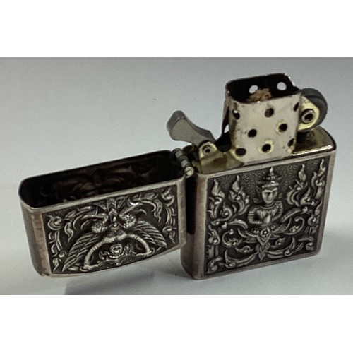 559 - A Thai silver lighter with hinged cover and chased decoration. Approx. 51 grams. Est. £30 - £40.