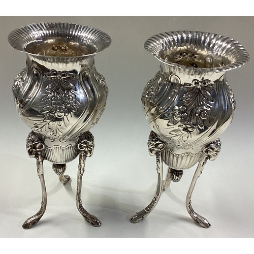 694 - A fine pair of Victorian silver vases on three feet embossed with flowers and rams. London 1887. By ... 