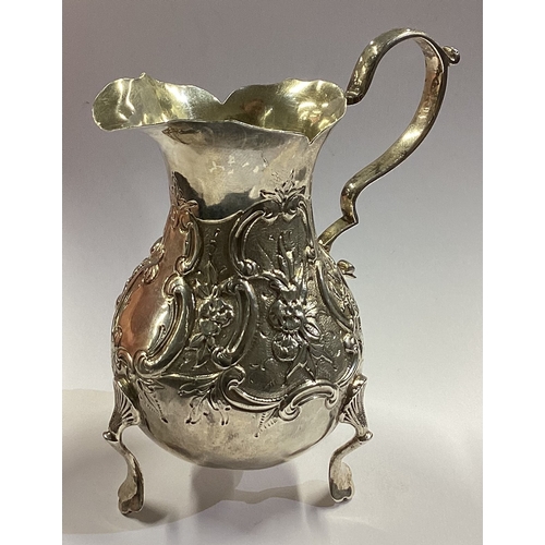 112 - DUBLIN: A chased Irish silver jug on feet. 1885. By West & Son. Approx. 71 grams. Est. £80 - £120.