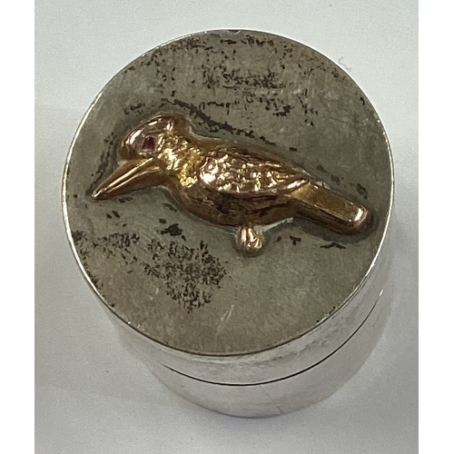 241 - An Australian silver and gold pill box chased with bird decoration. Approx. 24 grams. Est. £100 - £1... 