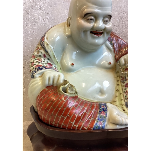 403 - A Chinese figure of a Buddha in seated position on carved stand. Marked to base. Est. £200 - £300.