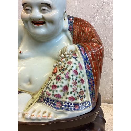 403 - A Chinese figure of a Buddha in seated position on carved stand. Marked to base. Est. £200 - £300.