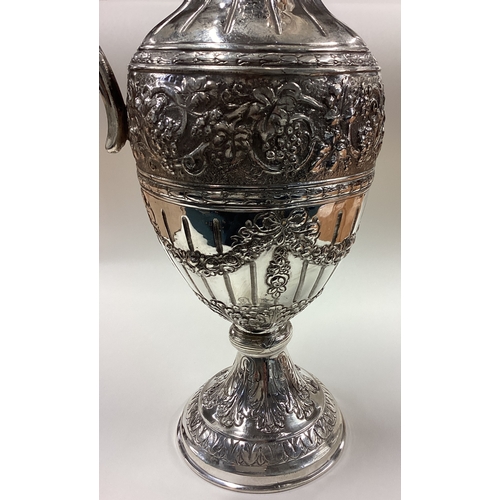 319 - A large Naturalistic German silver wine jug embossed with flowers, vines and grapes. Marked to foot.... 