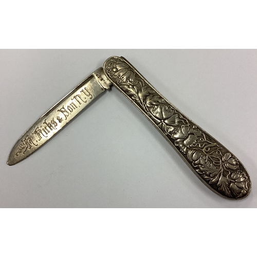 575 - An American silver travelling knife embossed with flowers. Approx. 28 grams. Est. £30 - £40.