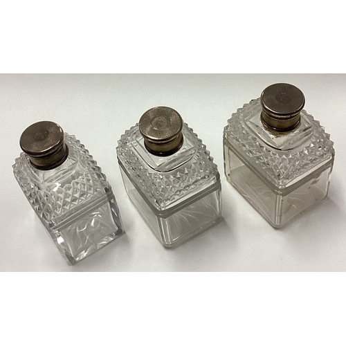 85 - A suite of three engine turned silver perfume bottles. Est. £50 - £80.