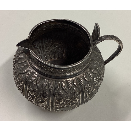 193 - A chased Indian silver cream jug of circular form with figural cobra handle. Approx. 100 grams. Est.... 