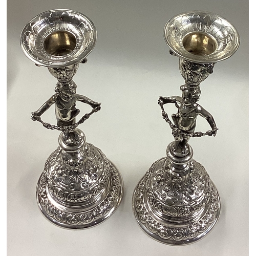 204 - A fine pair of 19th Century silver candlesticks in the form of cherubs chased with floral and figura... 