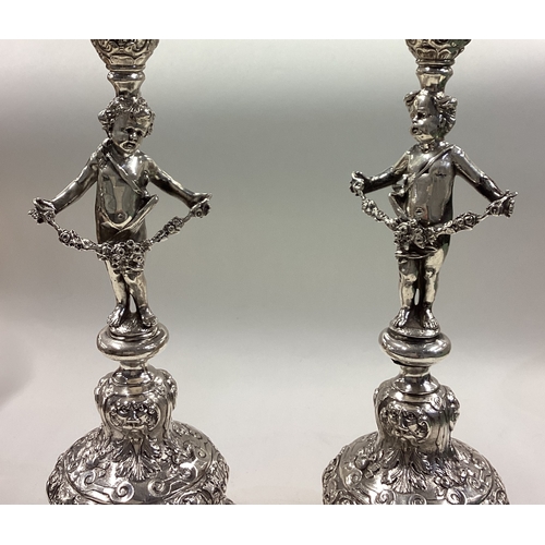 204 - A fine pair of 19th Century silver candlesticks in the form of cherubs chased with floral and figura... 