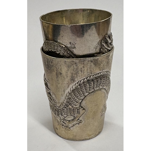 666 - A pair of Chinese export silver stacking beakers embossed with dragon decoration. Approx. 52 grams. ... 