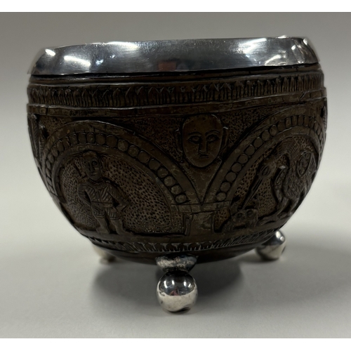 174 - A rare 19th Century Indian silver-mounted coconut cup carved with elephant decoration on ball feet. ... 