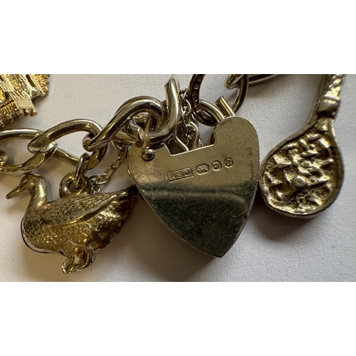 43 - A silver curb link charm bracelet with heart-shaped padlock. Approx. 42 grams. Est. £30 - £40.