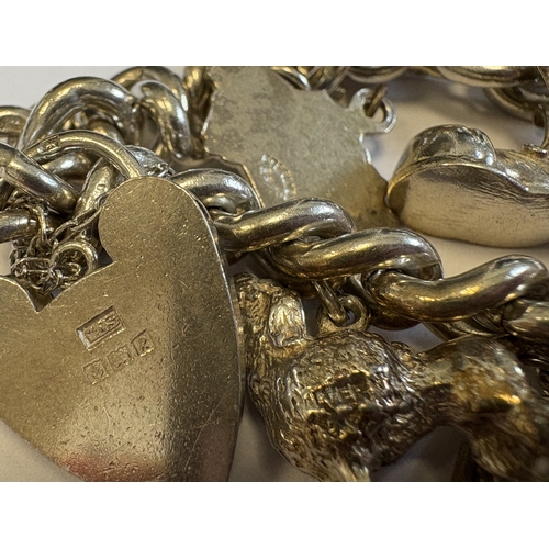 44 - A good silver curb link charm bracelet with heart-shaped padlock. Approx. 70 grams. Est. £40 - £60.