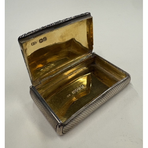 698 - An engine-turned Victorian silver snuff box with chased floral decoration to hinged cover and gilt i... 