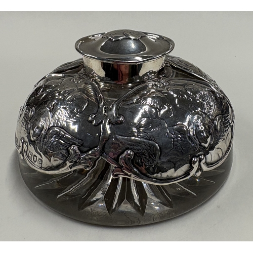 558 - A heavy Victorian silver-mounted glass inkwell chased with cherub decoration. London 1900. By Willia... 