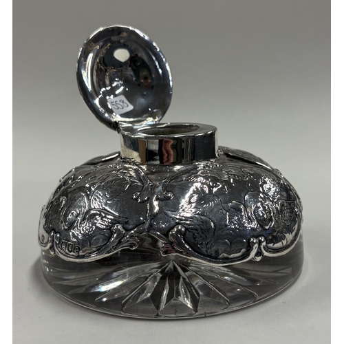 558 - A heavy Victorian silver-mounted glass inkwell chased with cherub decoration. London 1900. By Willia... 