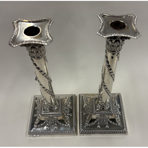 691 - A good pair of silver candlesticks on square bases with gadroon rims. Sheffield 1893. By Hawksworth,... 