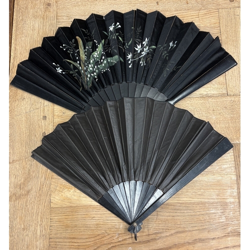 308 - An attractive ebony fan decorated with flowers together with one other. Est. £20 - £30.