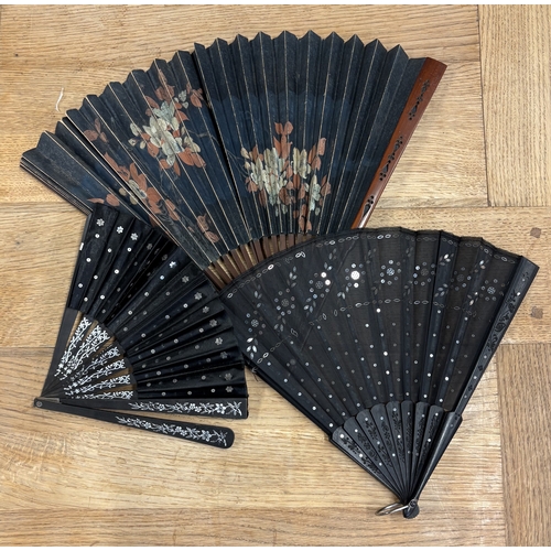 311 - An ebony and inlaid fan together with two others. Est. £20 - £30.