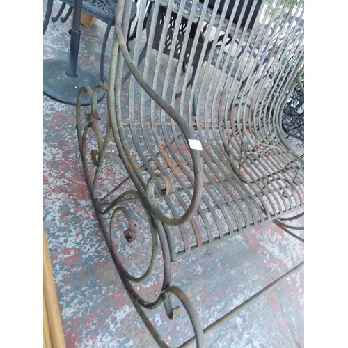 17 - A BLACK METAL ORNATE TWO SEAT ROCKING GARDEN CHAIR