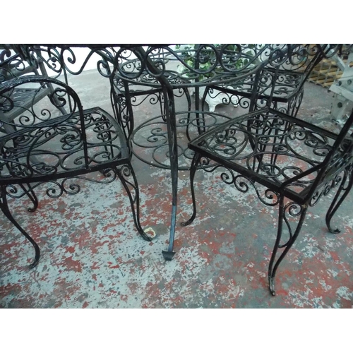 18 - A BLACK METAL ORNATE CIRCULAR GARDEN TABLE WITH FOUR MATCHING CHAIRS