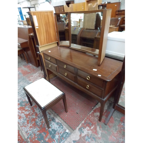 597 - A STAG MAHOGANY DRESSING TABLE WITH SIX DRAWERS, THREE SECTIONED MIRROR AND A STOOL