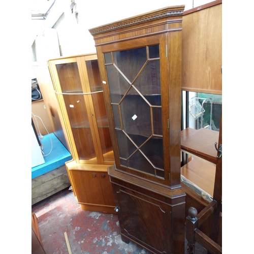 603 - A FLAMED MAHOGANY FREESTANDING CORNER CABINET WITH ONE GLAZED DOOR AND ONE LOWER DOOR