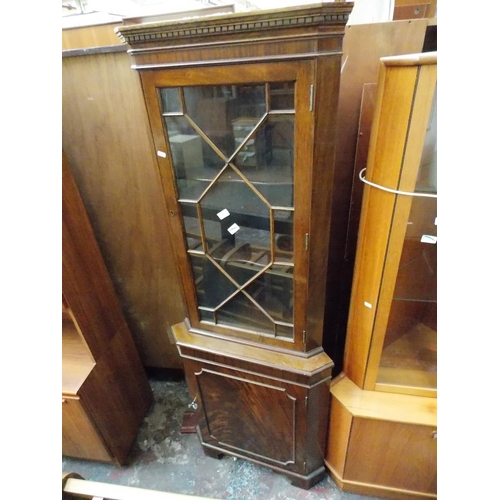 603 - A FLAMED MAHOGANY FREESTANDING CORNER CABINET WITH ONE GLAZED DOOR AND ONE LOWER DOOR