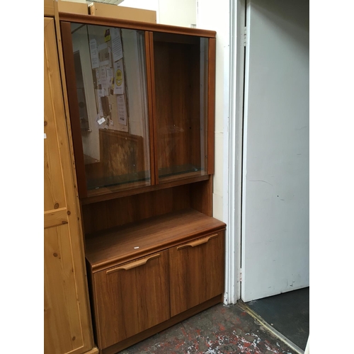 549 - A TEAK EFFECT DRESSER WITH TWO GLASS DOORS AND TWO LOWER DOORS