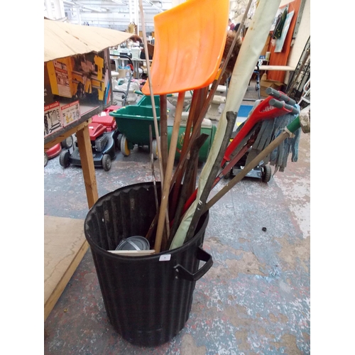 82 - A BLACK PLASTIC DUSTBIN CONTAINING HOE, BRUSH, WALKING STICK ETC