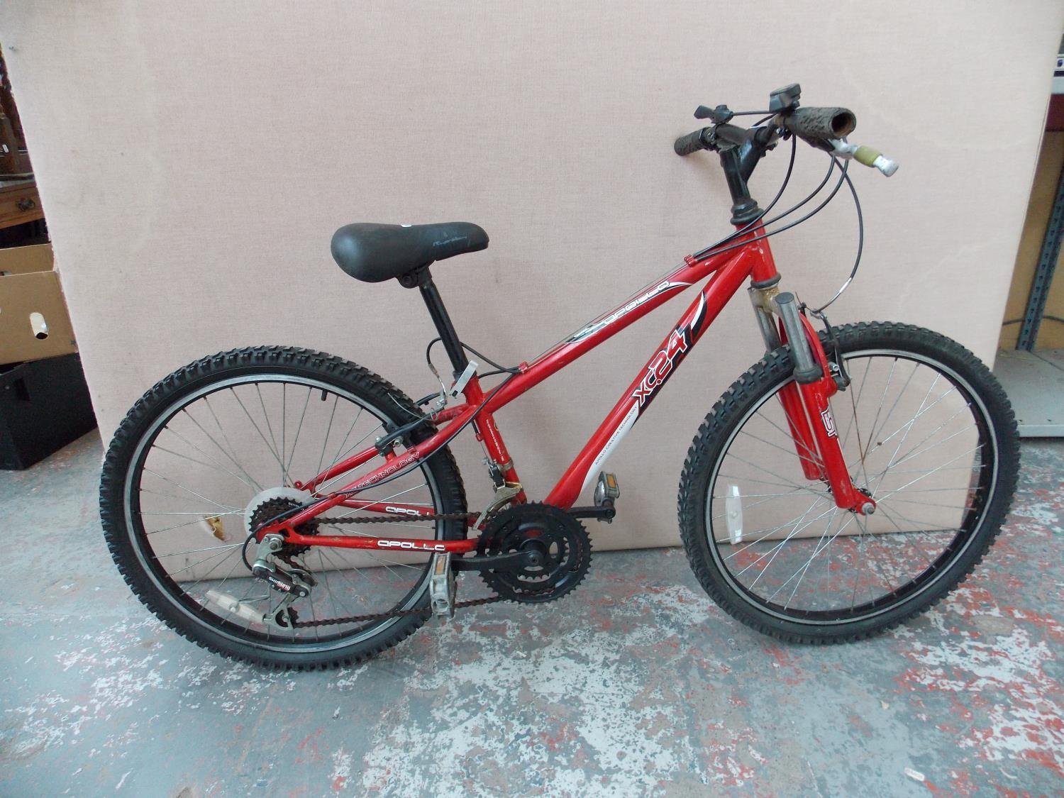 A RED APOLLO XC24 BOYS MOUNTAIN BIKE WITH FRONT SUSPENSION AND 18