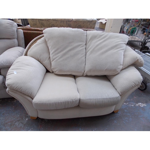 394 - A BEIGE UPHOLSTERED TWO SEATER SOFA