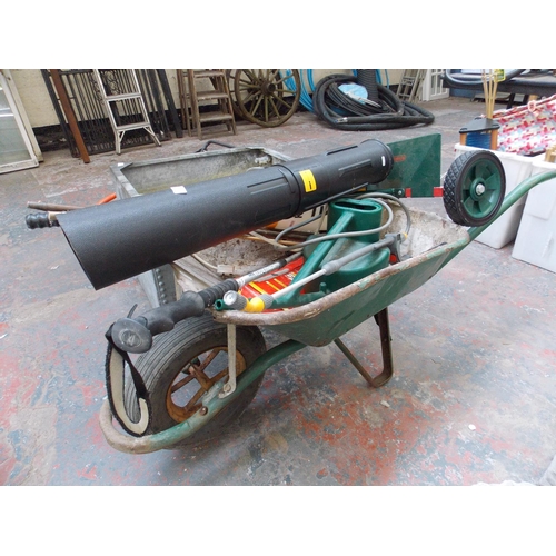 93 - A GREEN METAL BUILDERS WHEELBARROW CONTAINING HOSE LOCK, WEED SPRAYER, BOSMERE MANUAL LAWN RAKER, WA... 